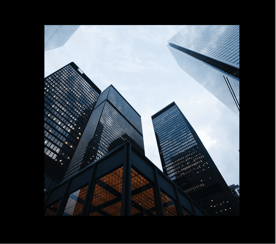 Upward view of modern skyscrapers in the heart of a financial district, capturing the sleek sides and tops of towering buildings.