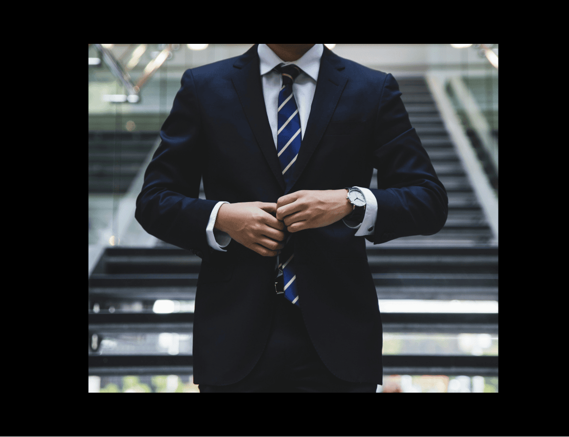 Man in a suit standing against a backdrop of a bustling financial district.