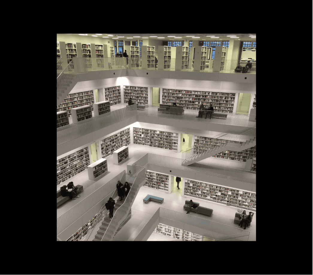 Panoramic view inside a spacious, modern library featuring five floors of bookshelves, with a staircase leading across the open space. The library includes quiet areas for sitting, reading, and learning.